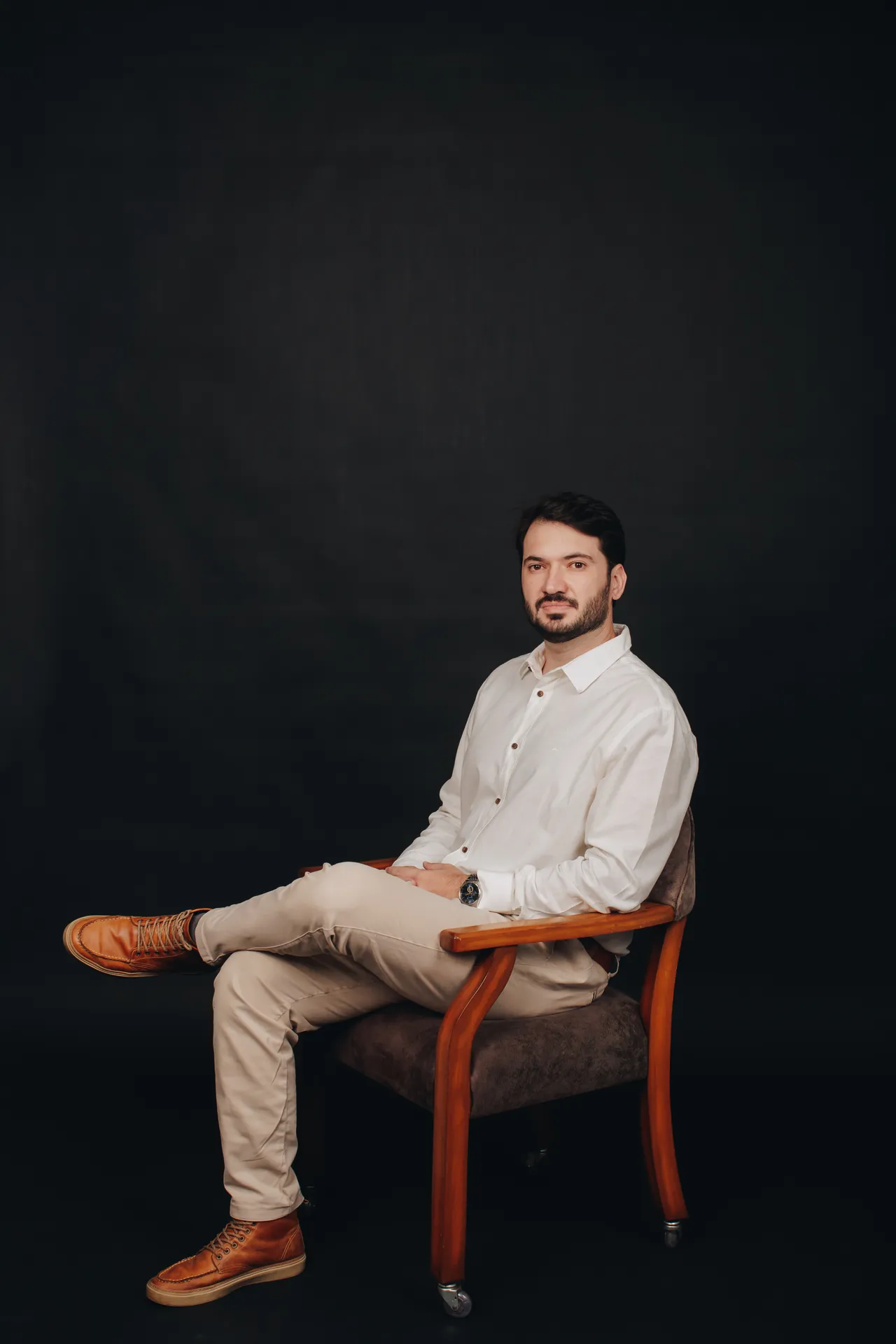 Dr. Iago Davanço sentado em uma poltrona de madeira